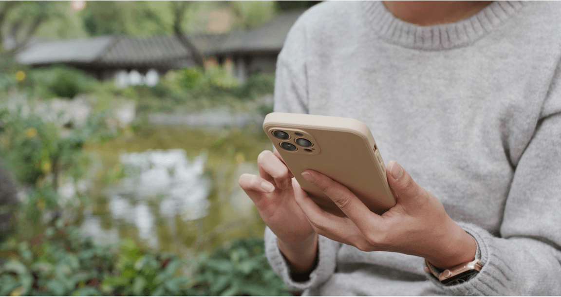 Een jongere typt op een smartphone in de natuur.